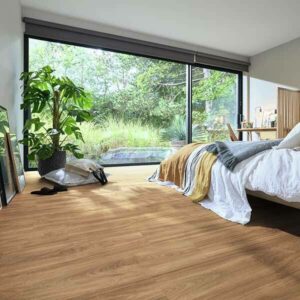 Ein minimalistisches Schlafzimmer mit Parkettboden und einer großen Fensterwand, die in den Garten führt. Der Raum ist einfach eingerichtet.